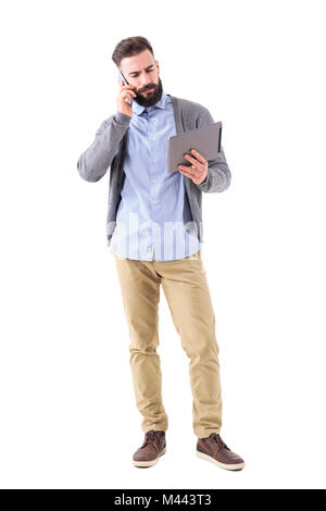 Ernsthafte gestressten Geschäftsmann am Telefon zu sprechen und auf der Suche nach Tablet Computer. Voller Körper Länge Porträt auf weißem studio Hintergrund isoliert. Stockfoto