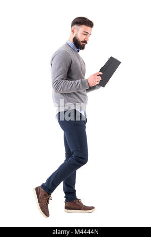 Locker lässig Geschäftsmann Wandern und Lesen notebook. Voller Körper Länge Porträt auf weißem studio Hintergrund isoliert. Stockfoto