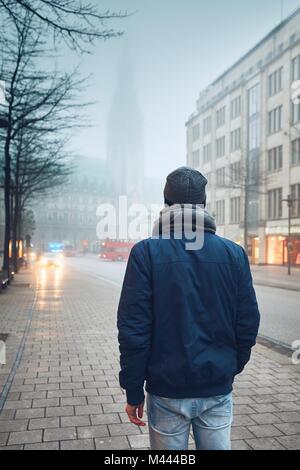Mann auf der Straße in düsteren Nebel Tag gegen Verkehr mit Antworten Emergency Medical Service. Hamburg, Deutschland. Stockfoto