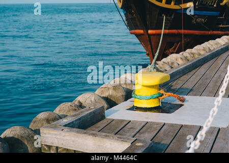 Festmachen Poller auf einem hölzernen Pier mit einem angedockten Piratenschiff im Hintergrund Stockfoto