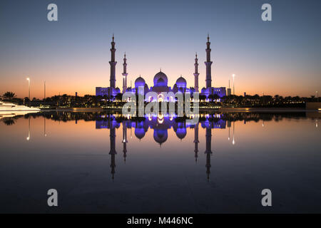 Sheikh Zayed Grand Moschee und es ist perfekt Reflexion in einem Pool mit Wasser während der Dämmerung nach Sonnenuntergang. Abu Dhabi, VAE. Stockfoto