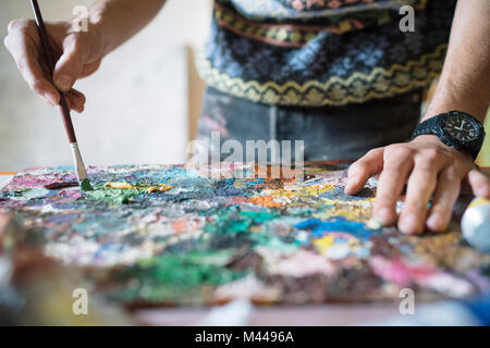Männliche Künstler mischen Ölfarbe auf Palette in Künstler Studio, von Hand schließen Stockfoto