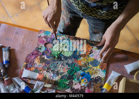 Männliche Künstler mischen Ölfarbe auf Palette in Künstler Studio, mittlere Partie Stockfoto