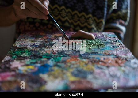 Männliche Künstler mischen Ölfarbe auf Palette in Künstler Studio, Nahaufnahme, Detail Stockfoto