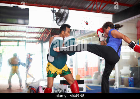 Reife Frau üben Kickboxen mit männlichen Trainer im Fitnessraum Stockfoto