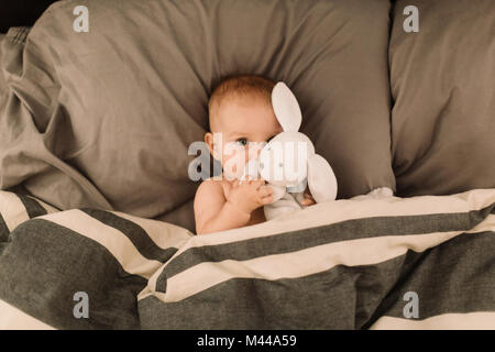 Portrait von baby girl im Bett umarmen toy Hase liegend, Ansicht von oben Stockfoto