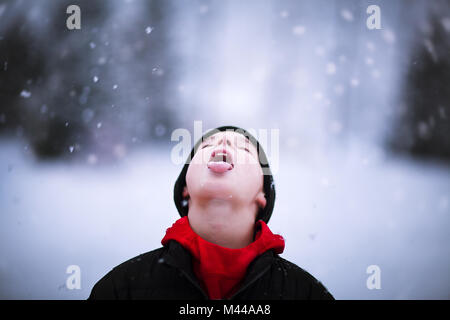 Porträt der Jungen fangen fallenden Schnee auf der Zunge Stockfoto