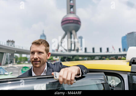 Junge Unternehmer aus yellow cab in Shanghai Financial Center, Shanghai, China Stockfoto