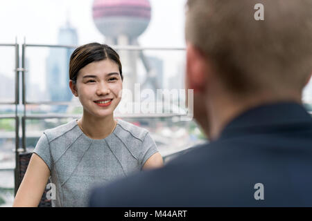 Blick über die Schulter der jungen Geschäftsfrau und Mann, Treffen im Straßencafé in Shanghai Financial Center, Shanghai, China Stockfoto