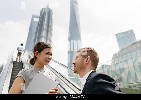 Junge Unternehmer und Frau Fahrtreppe in Shanghai Financial Center, Shanghai, China Stockfoto