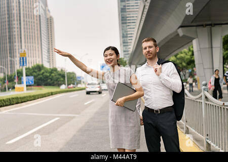 Junge Geschäftsfrau und man kommt mit dem Taxi in die Stadt, Shanghai, China Stockfoto