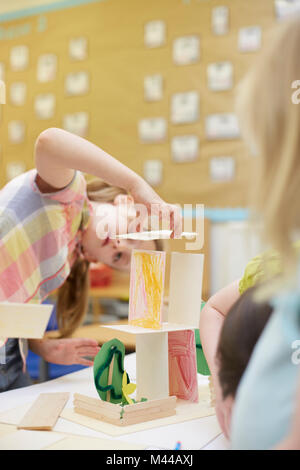 Primäre Schülerin einen Karton Struktur auf Klassenzimmer Schreibtische Stockfoto