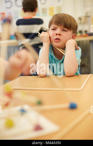 Primäre Schuljunge mit Plastik Strohhalme auf Klassenzimmer Schreibtische Stockfoto