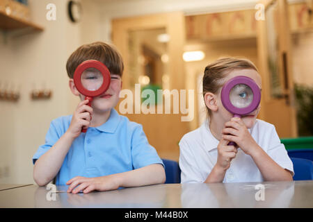 Schüler und Mädchen schauen durch Lupen im Unterricht in der Grundschule, Porträt Stockfoto