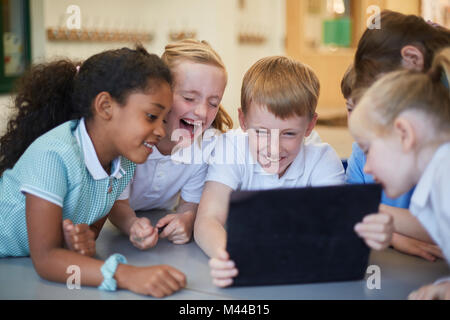 Schülerinnen und Schüler an der digitalen Tafel im Klassenzimmer lachend an der Grundschule Stockfoto