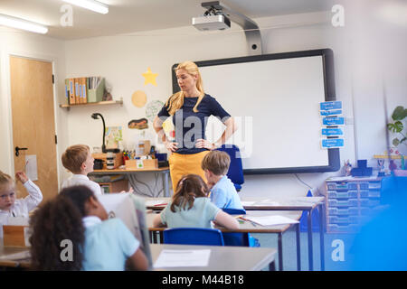 Lehrer mit den Händen auf den Hüften vor der Klasse in der Grundschule Stockfoto