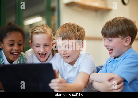 Schülerinnen und Schüler an der digitalen Tafel im Klassenzimmer lachend an der Grundschule