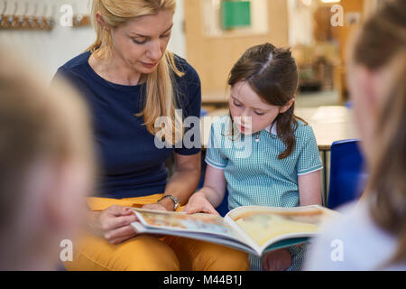 Lehrer mit Schülerinnen lesen Storybook im Unterricht in der Grundschule Stockfoto