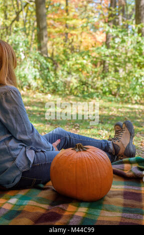 Zurück Blick auf eine Person sitzt auf einer Decke im Park mit Kürbis im Herbst Gefühl dankbar Stockfoto