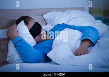 Nahaufnahme von einem Mann schlafen auf Bett mit Augenmaske Stockfoto