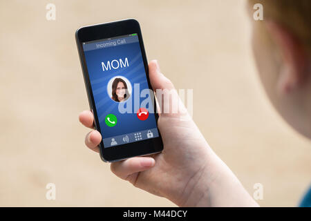Nahaufnahme einer Hand, die Smart Phone mit Mama des eingehenden Anrufs auf dem Display Stockfoto
