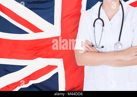 Nahaufnahme einer Ärztin mit gefalteten Händen stehend gegen Britische Flagge Stockfoto