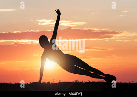 Silhouette der ausübende Person gegen die drastischen Himmel bei Sonnenuntergang Stockfoto