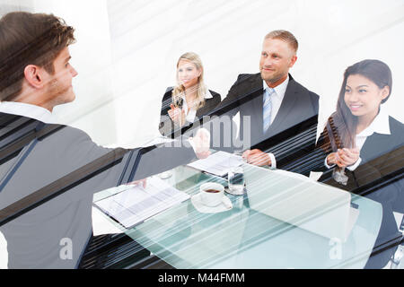 Doppelbelichtung manager zitternden Hand mit den Bewerberländern während Geschäftsfrauen applaudieren am Schreibtisch im Büro Stockfoto