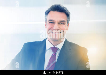 Portrait von Reifen Geschäftsmann in Anzug lächelnd im Büro Stockfoto