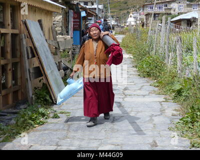 Manang, Nepal, 13. September 2015: Nepalesische Mönch Frau trägt wc Schüssel in Manang Dorf - Treffen der lokalen Bevölkerung bei der Annapurna Circuit Trek in N Stockfoto