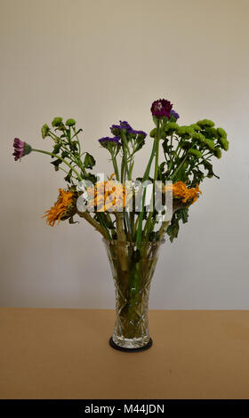 Ein Bündel von sterbenden Blumen in einer Glasvase. Stockfoto
