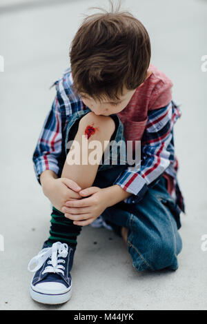 Porträt eines umgekippten Junge an seinem Knie gekratzt suchen Stockfoto