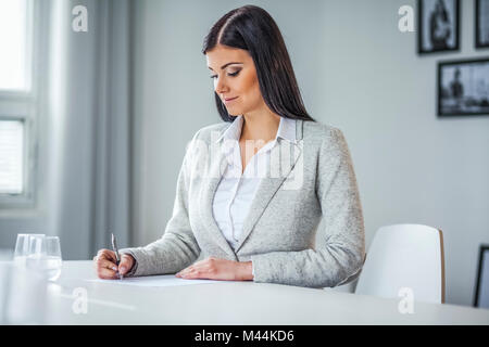 Schöne junge geschäftsfrau Schreiben auf Dokument in Office Stockfoto