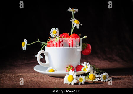 Kamillen und Erdbeeren in der Tasse Stockfoto