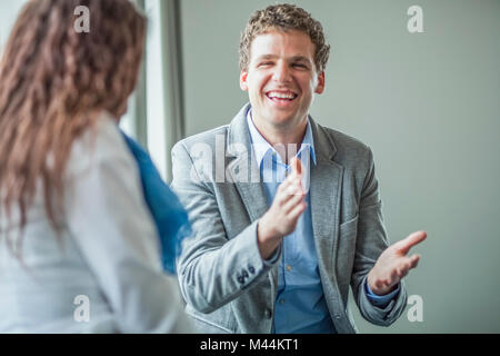 Fröhliche junge Unternehmer diskutieren mit Kollegen im Büro Stockfoto