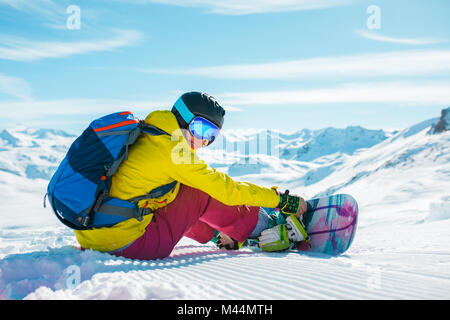 Bild der Frau in der Helm mit Rucksack auf Schnee mit Snowboard im Winter Resort Stockfoto