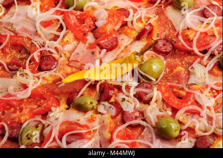 Pizza mit Salami, Peppeeoni, Oliven, Tomaten und gelbe Paprika Stockfoto