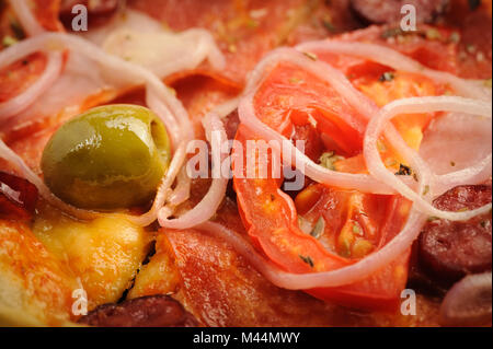 Pizza mit Salami, Peppeeoni, Oliven, Tomaten und gelbe Paprika Stockfoto