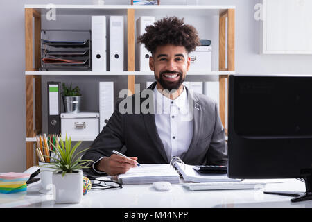 Portrait einer jungen Glücklich Geschäftsmanns, der im Büro Stockfoto