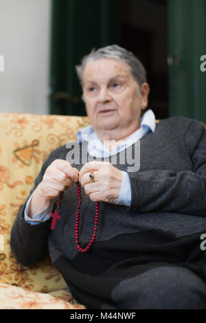 Ältere Frau zu beten selektiven Fokus auf Händen und Rosenkranz, Christentum religion Lebensstil Stockfoto