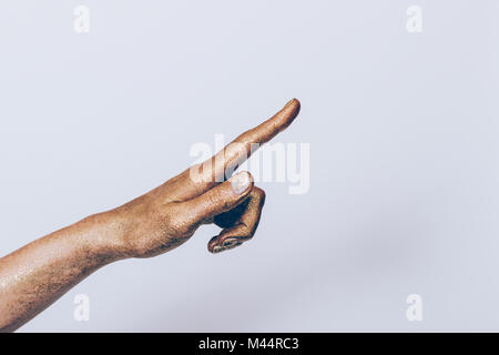 Weibliche Hand in Golden glitter mit weißen Maniküre zeigt die Richtung mit dem Zeigefinger Stockfoto