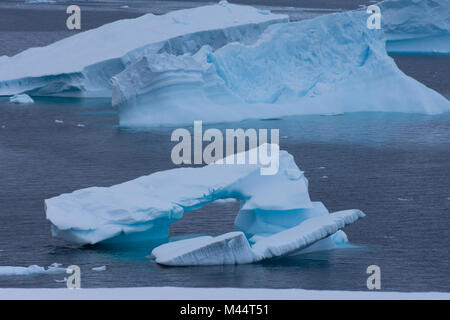 Eine Türkisblaue, gewölbte Eisberg in Charlotte Bay, Antarktis floating in die graue, blaue Wasser des Südlichen Ozeans. Stockfoto