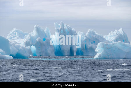 Eine leichte und mittlere Blaue Eisberge schwimmen im dunklen grau Wasser des Südlichen Ozeans in der Antarktis. Bedecktem Himmel ist oben. Stockfoto