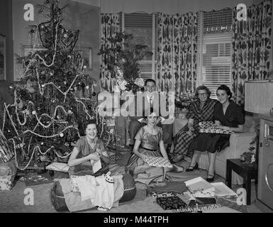 Amerikanische Familie versammelt sich um den Baum stellt am Weihnachtsmorgen zu öffnen, Ca. 1960. Datei name: Stockfoto