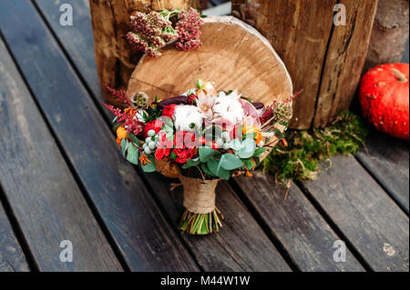 Wedding Bouquet mit Baumwolle und Pfingstrose im rustikalen Stil mit Holzboden. Holz- Stümpfe und Kürbisse auf Hintergrund Stockfoto