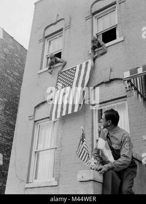 Pfadfinder hängen uns Flaggen aus dem Fenster eines Chicago Gebäude, Ca. 1960. Stockfoto