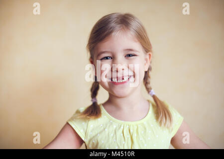 Happy verlorenen Zahn Little girl portrait, studio Schießen auf dem gelben Hintergrund Stockfoto