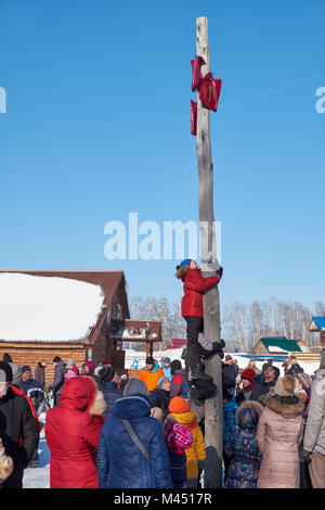 Nowosibirsk, Russland - Januar 11, 2018: Junge klettern auf eine hölzerne Stange für den Preis. Slawische Volksmusik Festlichkeiten oder Fastnacht Maslenitsa. Historische ein Stockfoto