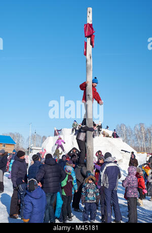 Nowosibirsk, Russland - Januar 11, 2018: Junge klettern auf eine hölzerne Stange für den Preis. Slawische Volksmusik Festlichkeiten oder Fastnacht Maslenitsa. Historische ein Stockfoto