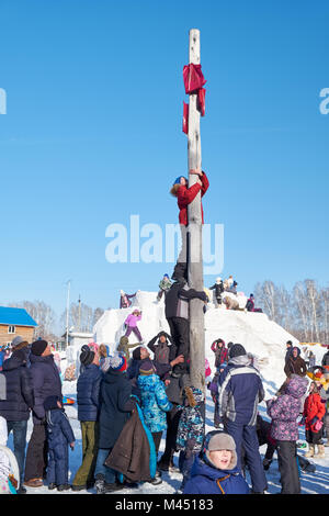 Nowosibirsk, Russland - Januar 11, 2018: Junge klettern auf eine hölzerne Stange für den Preis. Slawische Volksmusik Festlichkeiten oder Fastnacht Maslenitsa. Historische ein Stockfoto